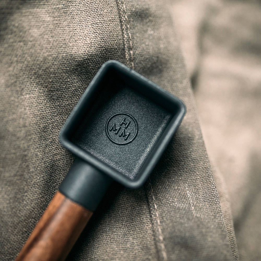 A cast iron coffee scoop with walnut wood handle.