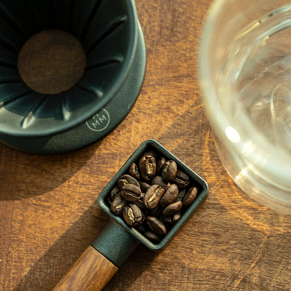 A cast iron coffee scoop with walnut wood handle.