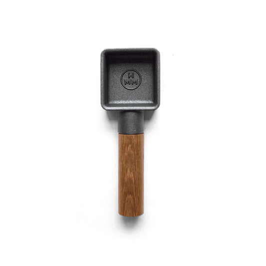 A cast iron coffee scoop with walnut wood handle.
