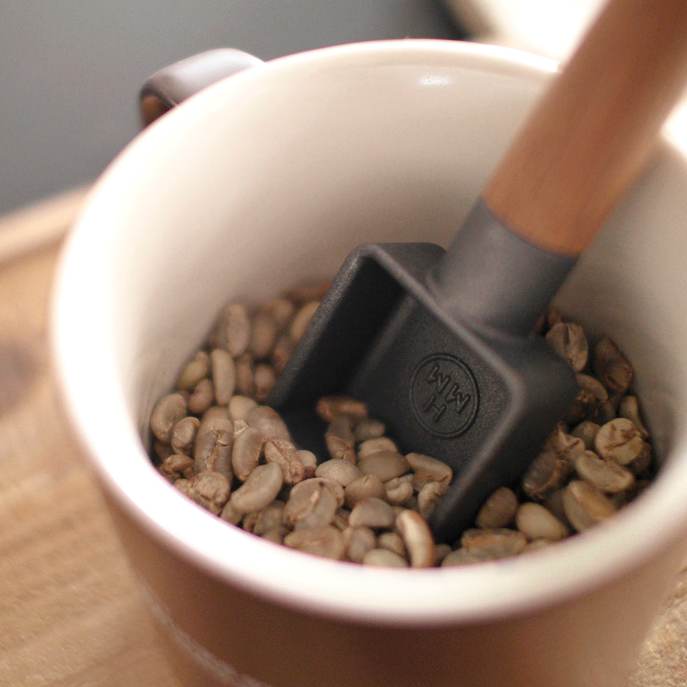 A cast iron coffee scoop with walnut wood handle.